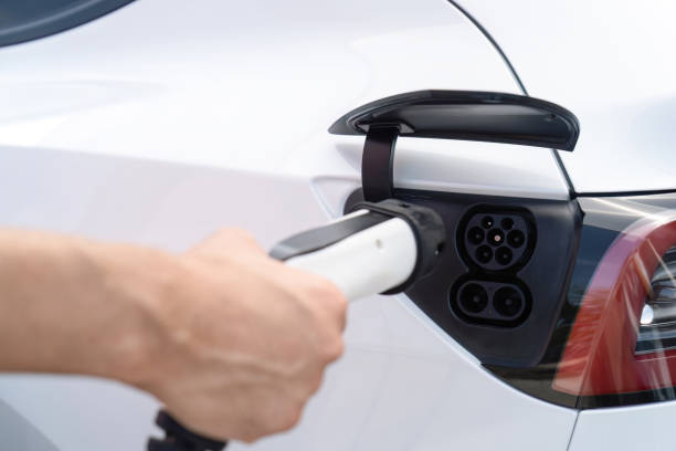 istock Hand insert EV charger plug into electric vehicle to recharge EV car. Perpetual 1981198763