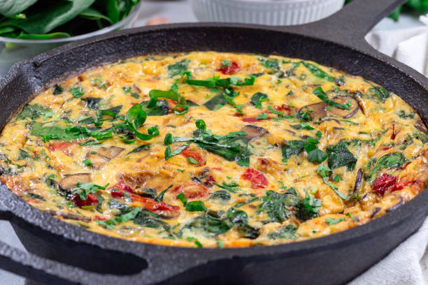 istock Egg frittata with spinach, roasted peppers, mushrooms, cheese, in cast iron, horizontal, closeup 1981225080