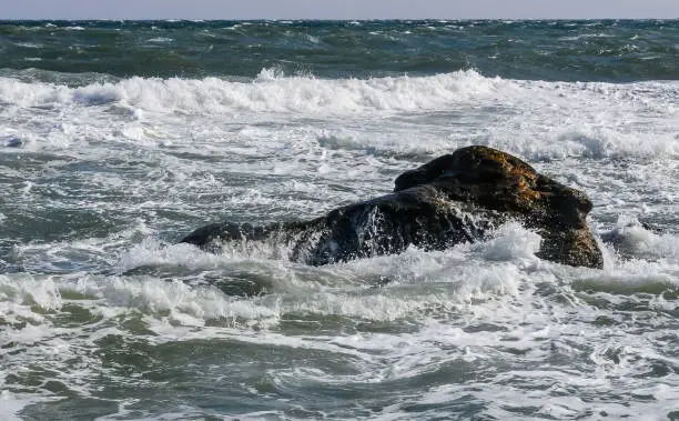 Waves break on a stone and white splashes of water fly into the air, Black Sea