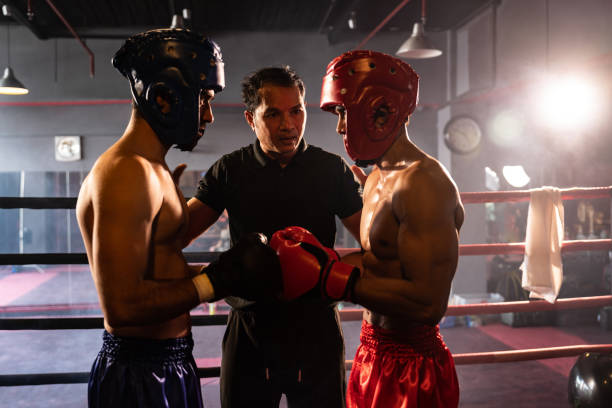 istock Boxer fighter with safety helmet face off with each other while referee. Impetus 1981275463