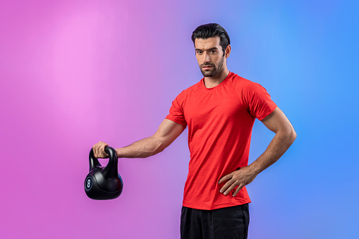 Full body length gaiety shot athletic and sporty man with kettlebell for weight lifting as bodybuilding exercise in standing posture on isolated background. Healthy active and body care lifestyle