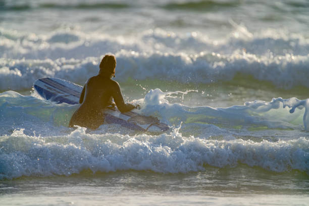 The Pacific Rim National Park on Vancouver Island on April  27, 2023: Young female entering the water for a surfing session at Pacific Rim National Park on Vancouver Island, British Columbia
