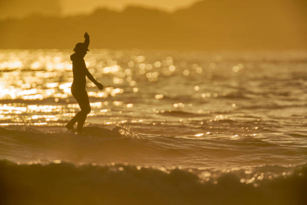 The Pacific Rim National Park on Vancouver Island on April  27, 2023:  Male engaged in surfing at Pacific Rim National Park on Vancouver Island at sunset, British Columbia