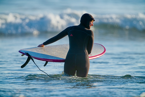The Pacific Rim National Park on Vancouver Island on April  28, 2023:  Young female entering the water for a surfing session at Pacific Rim National Park on Vancouver Island, British Columbia