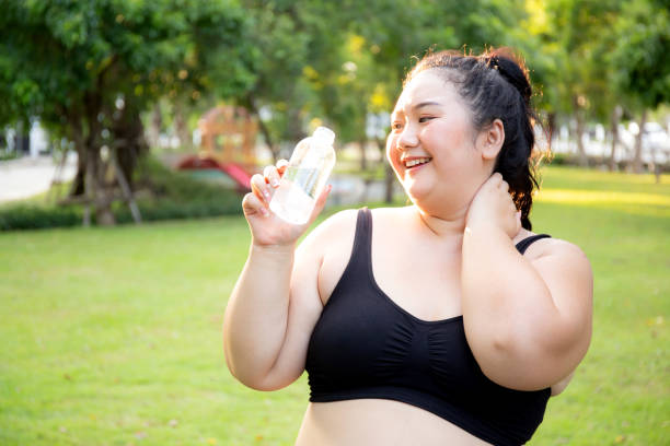 istock Active plus size woman hydration drinking a water bottle outdoors, taking a break during a sunny day exercise routine, fat woman drinking water after workout in garden, activity for health. 1981352327