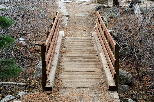 Wooden foot bridge on trail across small creek.  Winter.