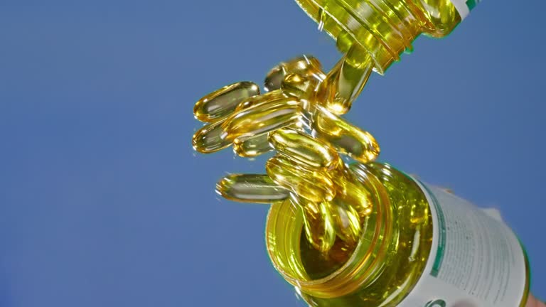 Close up of pouring fish oil vitamin gelatin capsules with Omega-3 on a blue background