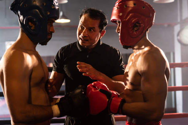 Boxer fighter with safety helmet face off with each other while referee. Impetus