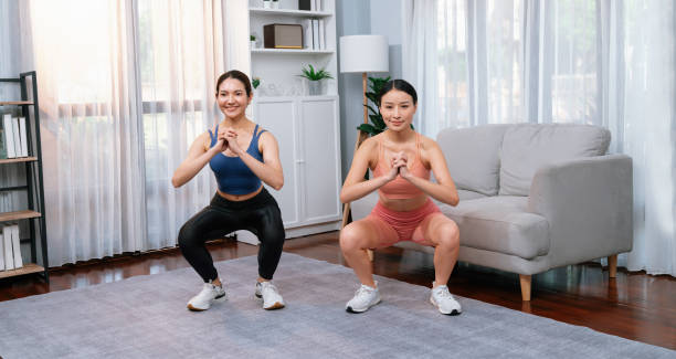 istock Vigorous energetic woman with trainer doing exercise at home with sport band. 1981552313