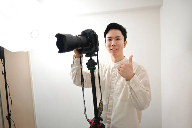 fotógrafo masculino jovem asiático tirando foto com câmera reflex de lente única no estúdio de fotografia - baby goods flash - fotografias e filmes do acervo