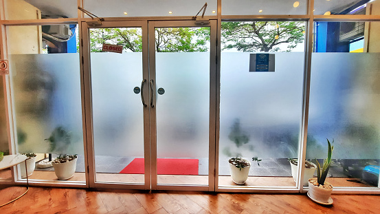 Aluminum glass door design equipped with automatic door closer. Glass wall with sunblast sticker
