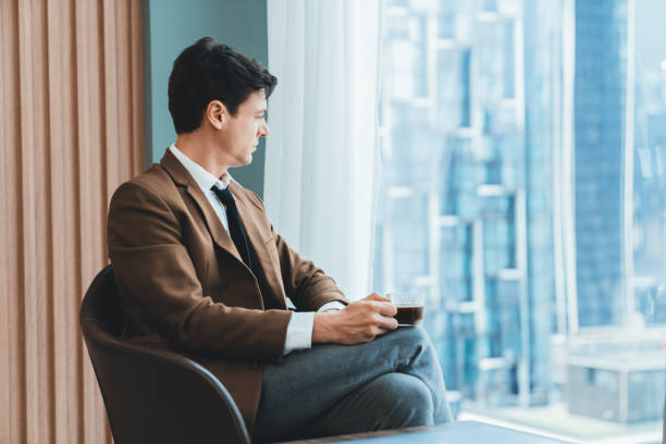istock Smart businessman holding coffee cup while looking skyscraper view. Ornamented. 1981633100