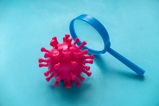 Virus model with magnifying glass.