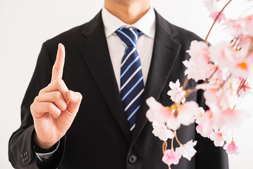 A Suit-Wearing Man Pointing with Index Finger and Cherry Blossoms