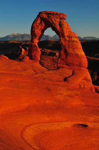 Sunset at the Delicate Arch and the distant La Sal Mountains, Arches National Park, Moab, Utah, USA.