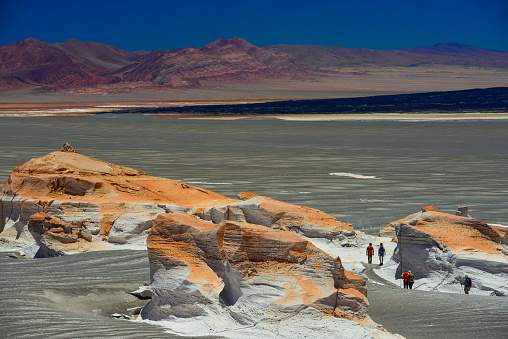 Female tourist looking at Laguna Colorada in Bolivia. The Altiplano (Spanish for high plain), in west-central South America, where the Andes are at their widest, is the most extensive area of high plateau on earth outside of Tibet. Lake Titicaca is its best known geographical feature. The Altiplano is an area of inland drainage (endorheism) lying in the central Andes, occupying parts of Northern Chile and Argentina, Western Bolivia and Southern Peru. Its height averages about 3,750 meters (12,300 feet), slightly less than that of Tibet. Unlike the Tibetan Plateau, however, the Altiplano is dominated by massive active volcanoes of the Central Volcanic Zone to the west like Ampato (6288 m), Tutupaca (5816 m), Nevado Sajama (6542 m), Parinacota (6348 m), Guallatiri (6071 m), Cerro Paroma (5728 m), Cerro Uturuncu (6008 m) and Licancabur (5916 m), and the Cordillera Real in the north east with Illampu (6368 m), Huayna Potosi (6088 m), Ancohuma (6427 m) and Illimani (6438 m). The Atacama Desert, one of the driest areas on the whole planet, lies to the southwest of the Altiplano. In contrast, to the east lies the humid Amazon Rainforest.