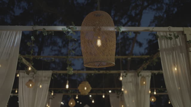 Hanging light bulb wedding decoration under tree outdoor party.