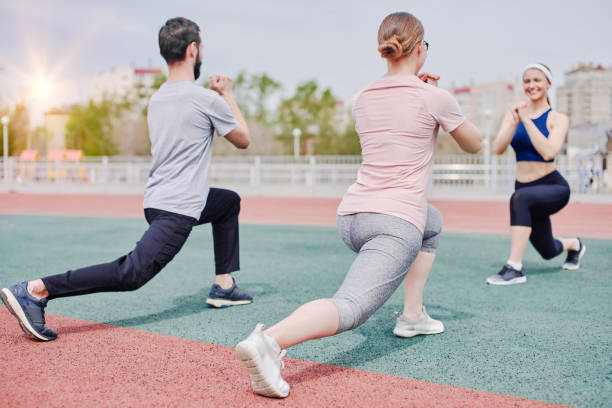 istock Warming up exercises for legs with a trainer outdoors 1981822668