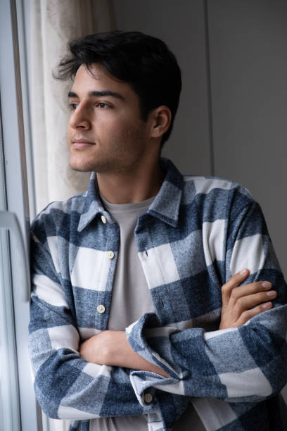 istock Handsome young man looking away from window 1981885274