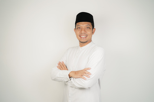 Happy and confident asian muslim man standing with crossed arms on white background