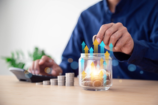 Man saving money concept. hand holding coins putting in jug glass , Planning step up, saving money for future plan, retirement fund , Concept business finance saving money and investment.