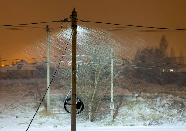 It's snowing at night in the light of a lantern on a pole.