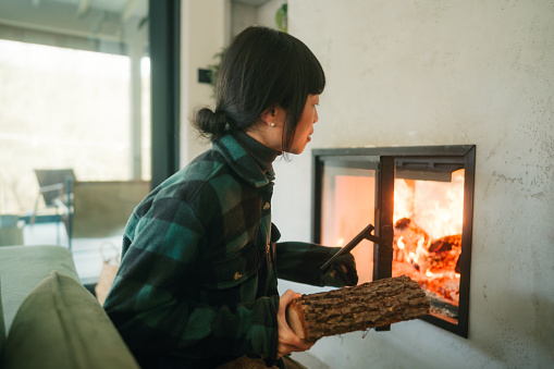 Photo of a Japanese woman adding wood to the fireplace