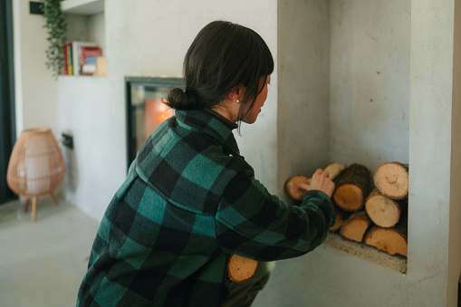 Photo of a Japanese woman adding wood to the fireplace