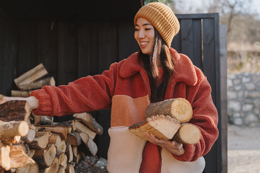 Photo of a Japanese woman bringing chopped firewood into the house