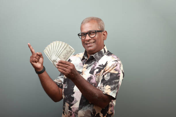 Happy Indian senior man holding a bunch of Indian currency notes in hand stock photo