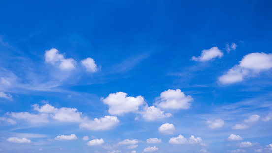 Group of white fluffy clouds floating on blue sky background, beautiful summer cloudscape in widescreen view