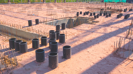 Deep foundation footing reinforcement steel with EFLEX corrugated hdpe pipes on the ground for reinforced concrete floor and electrical wiring system work in large factory construction site area