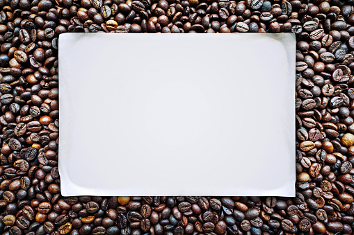 Blank white paper on roasted coffee beans background.