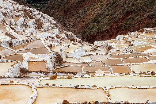 Maras, Peru, November 13, 2021: View of the Salineras de Maras - salt ponds located 3,000 meters above sea level in the Sacred Valley of the Incas. Since pre-Inca times, salt has been obtained here by evaporating salty water from a local subterranean stream.