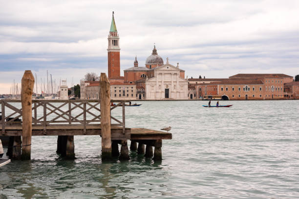 San Giorgio Maggiore Island in Venice, Italy, photographed with its iconic bell tower and serene surroundings under a vibrant blue sky, offering a glimpse into historical architecture and tranquil Venetian waters.