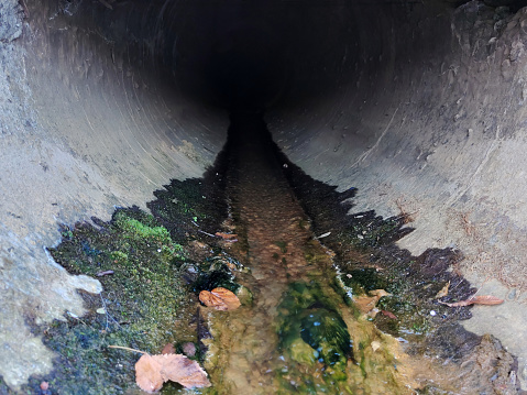 A perspective view of a sewer pipe from which underground sewage flows
