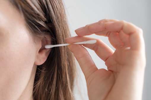 Woman cleaning her ear with a cotton swab
