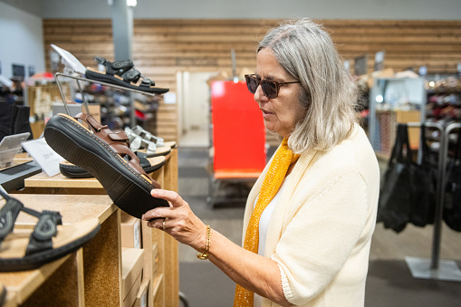 This is a photo of a senior hispanic woman in her 70s shoe shopping in Orlando, Florida.