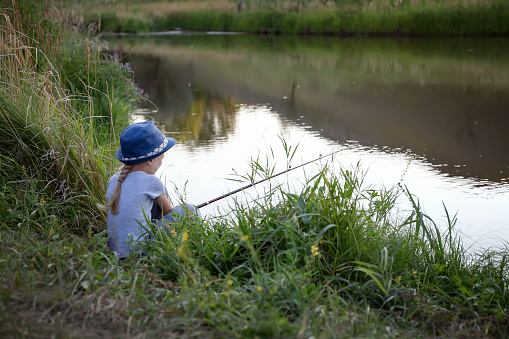 Teenage boy with a full stringer of walleyes on a sunny day with a lake and pine trees and fishing boats and some clouds