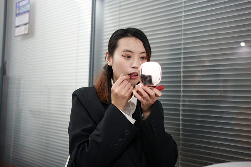 Young business woman applying makeup