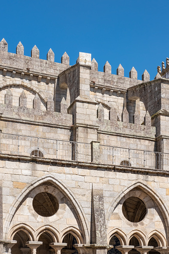 Porto, Portugal - September 26, 2022: detail of the Gothic architecture of the Se do Porto cathedral, showcasing intricate stonemasonry of the cloister arches, of roof spires and of flying buttresses.
