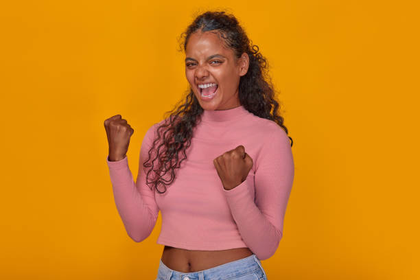 istock Young overjoyed Indian woman makes victory gestures stands in studio 1982247283
