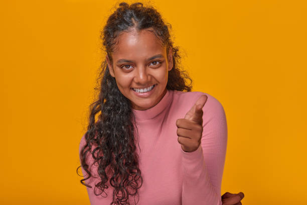 istock Young cheerful Indian woman with smile points finger at screen stands in studio 1982248335