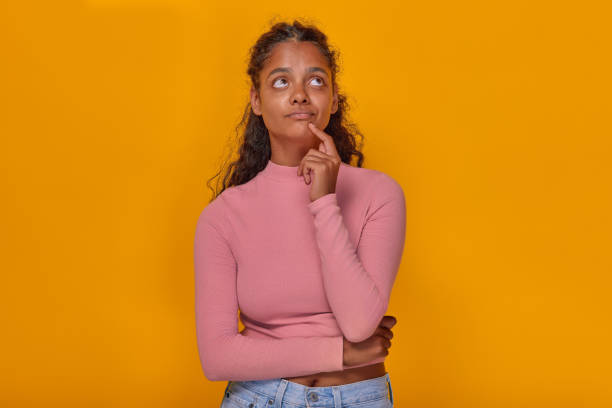 istock Young thoughtful attractive Indian woman student looks up stands in studio 1982251526