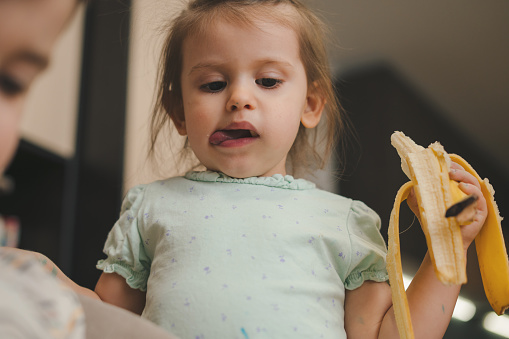 Portrait kid cute little girl holding banana for eating.