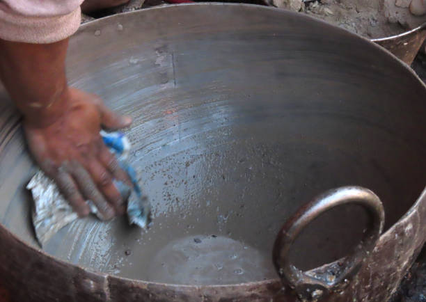 An action motion shot of a man cleaning a large cooking pot with sand and grit with a dirty cloth and water. The pot actually came up extremely clean, however good image for hygiene and sickness when traveling.
