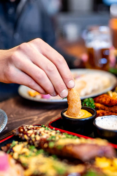 istock man hand dipping a fried shrimp tail in a cheese sauce. 1982324450