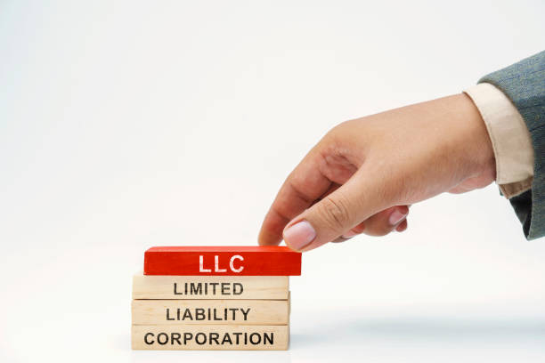 Business hand put wooden block stack with LLC - Limited Liability Company text stock photo