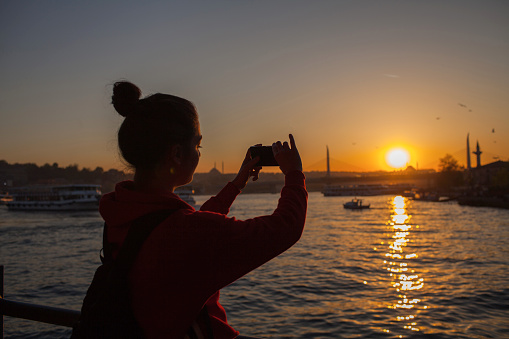 Young Woman Tourist is looking sunset view on Galata Bridge.