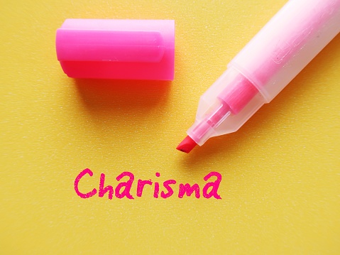 Pink highlight pen on yellow background with handwritten text CHARISMA, refers to people who have naturally ability to influence others, attract attention and admiration